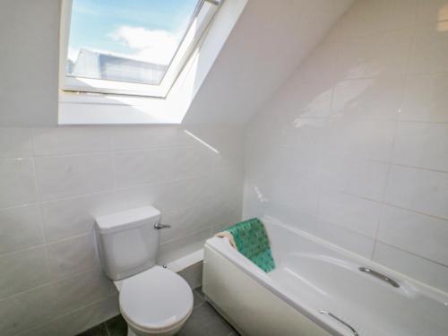 a bathroom with a toilet and a sink and a window at Beehive Cottage in Kilbrittain