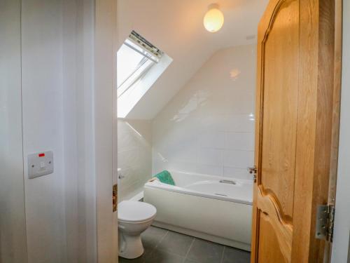 a bathroom with a toilet and a bath tub at Beehive Cottage in Kilbrittain