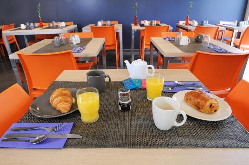 einen Tisch mit einem Frühstück mit Croissants und Orangensaft in der Unterkunft Residhome Clermont Ferrand Gergovia in Clermont-Ferrand