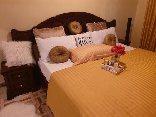 Una cama con almohadas y una bandeja de flores. en Jaja's One Bedroom near Ciala Resort Kisumu en Kisumu