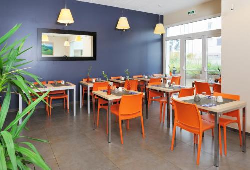 une salle à manger avec des tables et des chaises orange dans l'établissement Residhome Clermont Ferrand Gergovia, à Clermont-Ferrand