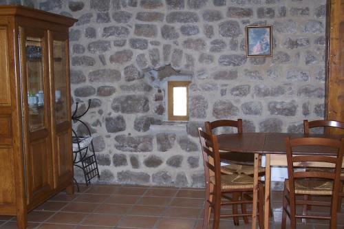 a dining room with a stone wall with a table and chairs at Domaine de Salomony in Marcols-les-Eaux