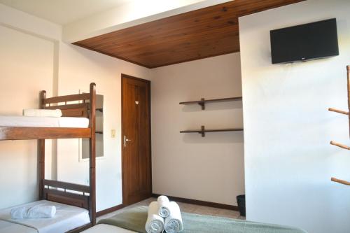 a bedroom with two bunk beds and a flat screen tv at Pousada da praça in Morro de São Paulo