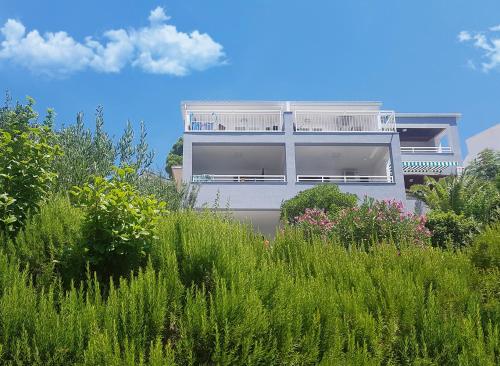 a white building in the middle of a field of grass at Villa Skalinada with sea view in Brela