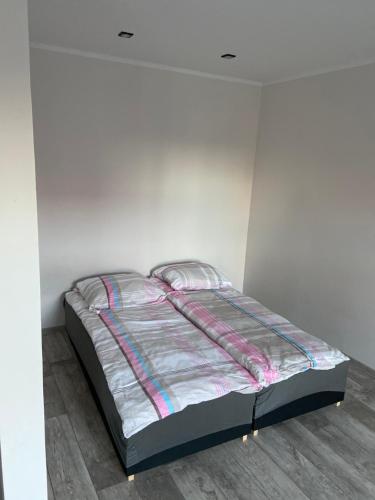 a bed in a room with a white wall at Apartamenty Bezrzecze in Szczecin