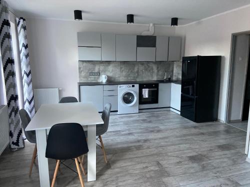 a kitchen with a table and chairs and a washing machine at Apartamenty Bezrzecze in Szczecin