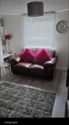 un sofá de cuero marrón en una sala de estar con reloj en New, spacious & immaculate Double room for rental in Colchester Town Centre!, en Colchester