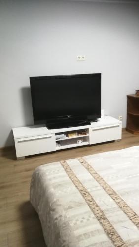 een flatscreen-tv zittend op een wit entertainment center bij Studio nearby the Kalnciema quarter in Rīga