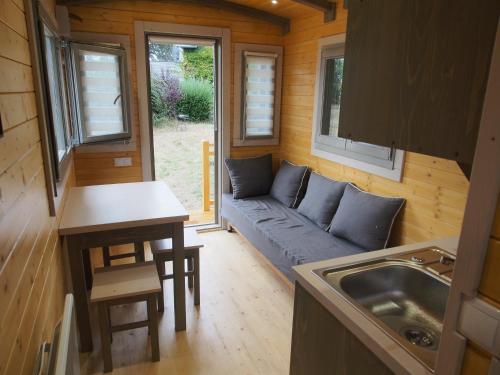 a small living room with a couch in a tiny house at Roulotte avec vue sur la mer, proche d'Etretat in Saint-Jouin-Bruneval