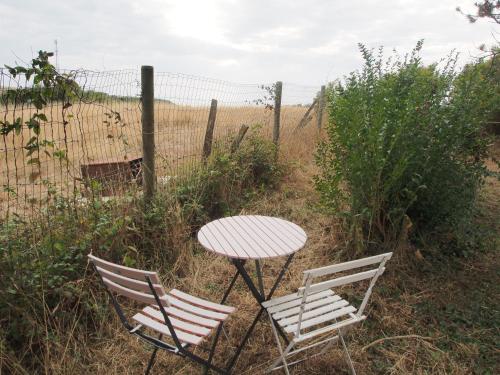Saint-Jouin-BrunevalにあるRoulotte avec vue sur la mer, proche d'Etretatのテーブルと椅子2脚、テーブルと柵