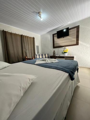 a bedroom with a large bed with a tv on the wall at POUSADA ALEFER in Matinhos