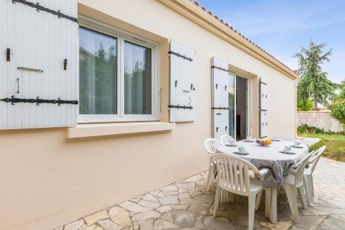 een patio met een tafel en stoelen voor een huis bij Nice house with a yard - La Rochelle - Welkeys in Puilboreau