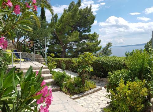a garden with stairs and flowers and the ocean at Villa Skalinada with sea view in Brela