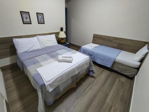 a hotel room with two beds and a table at AVENIDA HOTEL DE RESENDE in Resende