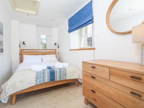 a bedroom with a bed with a mirror and a dresser at Linham Barn in Kingsbridge