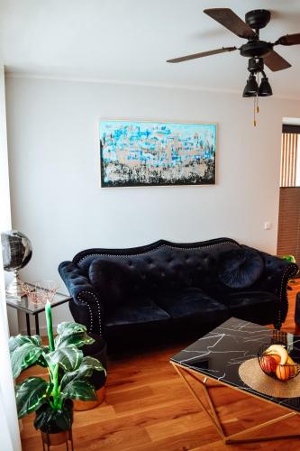 a black leather couch in a living room with a table at Albatross Dimants - apartamenti Rīgas jūras līča krastā in Ķesterciems