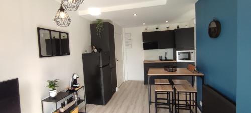 una pequeña cocina con nevera negra y mesa en Indy Appart - T2 moderne, calme, propre, parking, balcon vue, en Saint-Priest