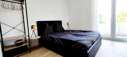 - une chambre avec un lit noir et 2 lampes dans l'établissement Indy Appart - T2 moderne - Clim - Parking - Balcon vue - Calme Propre, à Saint-Priest