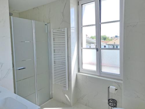 a white bathroom with a shower and a window at Superbe appartement T3 au centre plage .Parking in Hendaye