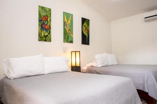 two beds in a room with paintings on the wall at Casa María Aeropuerto B&B in Alajuela City