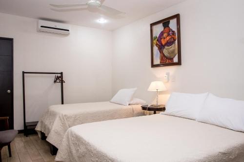 a room with two beds and a painting on the wall at Casa María Aeropuerto B&B in Alajuela