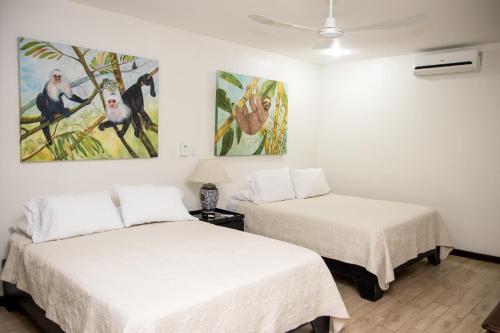 two beds in a room with paintings on the wall at Casa María Aeropuerto B&B in Alajuela City