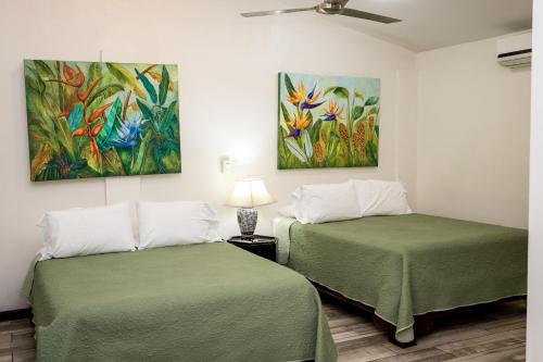 two beds in a room with paintings on the wall at Casa María Aeropuerto B&B in Alajuela