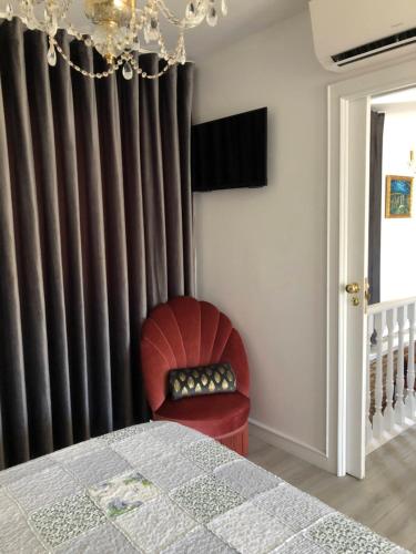 a bedroom with a red chair in front of a curtain at Casa Pedro e Inês in Viana do Castelo