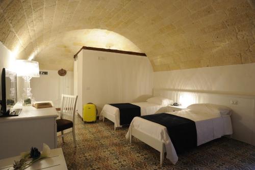 a hotel room with two beds and a desk and a room at Il Nido dei Falchi B&B in Altamura