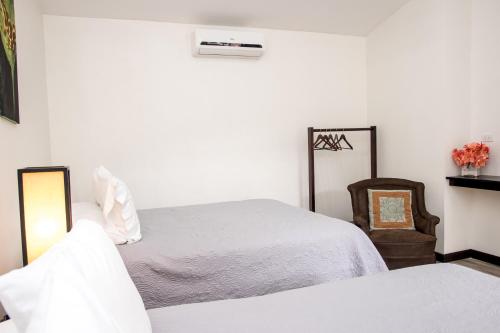 a bedroom with two beds and a chair at Casa María Aeropuerto B&B in Alajuela City