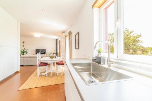a white kitchen with a sink and a table at Quinta da Asneira in Montemor-o-Novo