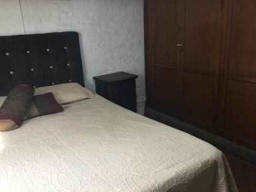 a bedroom with a white bed with a black headboard at Beautiful Colonial House in Cali