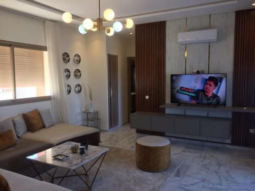 een woonkamer met een bank en een flatscreen-tv bij Rosa Park in Mohammedia