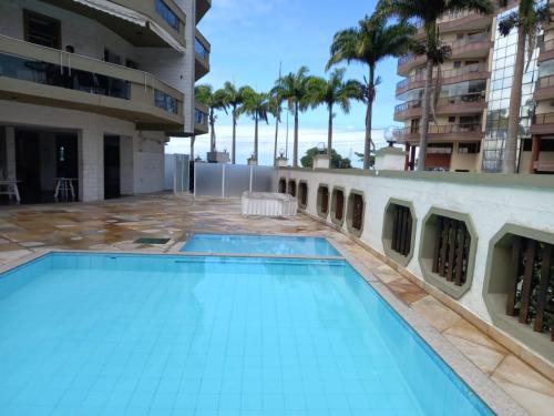 a swimming pool in the middle of a building with palm trees at Apartamento - CARIBE BRASILEIRO - Praia do Forte - De frente para o mar in Cabo Frio
