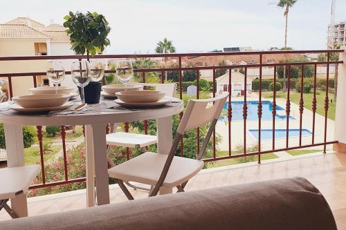 a table with chairs and wine glasses on a balcony at Lindo apartamento junto à praia e à Marina de Vilamoura com Piscina e Wi-Fi in Quarteira