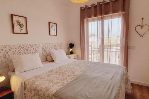 Un dormitorio con una cama grande y una ventana en Lindo apartamento junto à praia e à Marina de Vilamoura com Piscina e Wi-Fi, en Quarteira