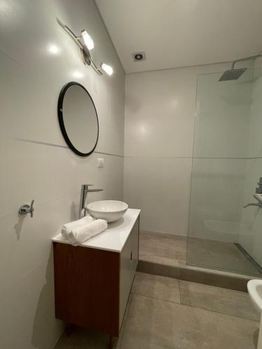 y baño con lavabo, espejo y ducha. en Departamento Moderno - Equipado y Con Cochera Privada en Mar del Plata