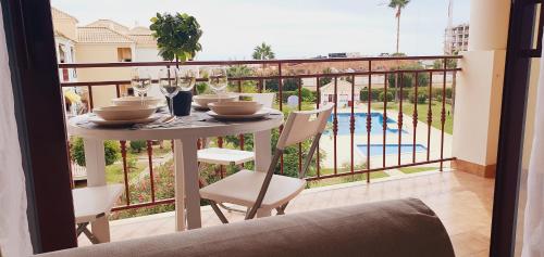 a table and chairs on a balcony with a view of a pool at Lindo apartamento junto à praia e à Marina de Vilamoura com Piscina e Wi-Fi in Quarteira