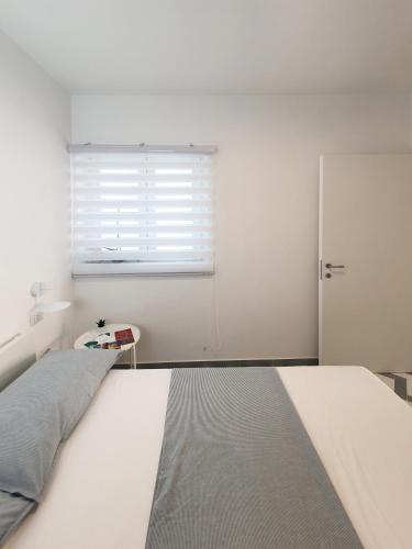 a white bedroom with a bed and a window at La Casa di Mina in Monte di Procida