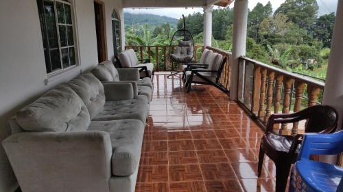 a living room with a couch and chairs on a balcony at Agartha Hostel in Boquete