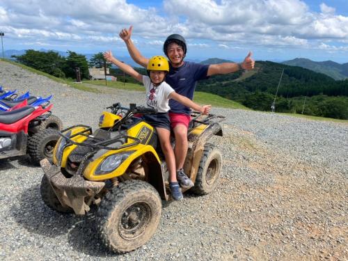 a man and a child on atvs on a mountain at Mineyama Kogen Hotel Relaxia in Kamikawa