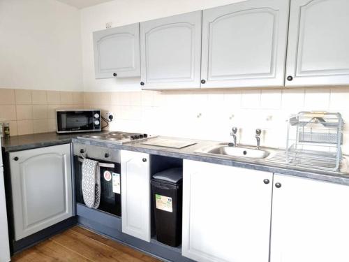 a kitchen with white cabinets and a sink at Two Bed Holiday Home with Free Parking in Inverness in Inverness