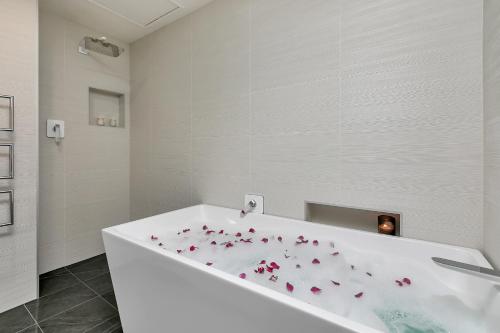 uma casa de banho com uma banheira branca com flores cor-de-rosa em Penthouse Premier em Auckland