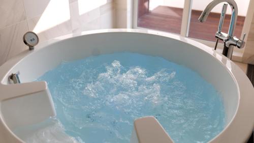 a tub filled with blue water in a bathroom at Soukyu 蒼穹 #TB1 in Yonago