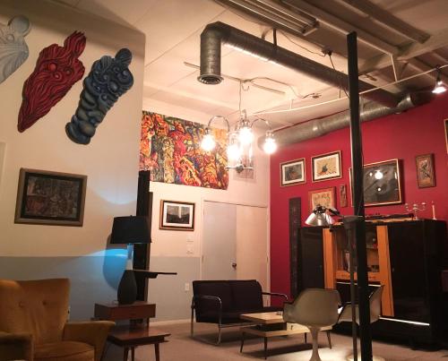 a room with red walls with chairs and artwork at SPACE CASTLE: a 1950s Gas Station transformed into an Art Themed Wonderland in Truth or Consequences