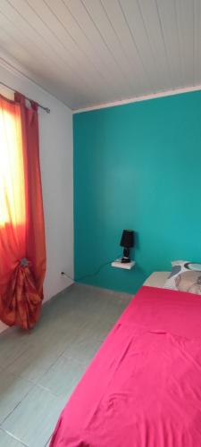 a bedroom with a pink bed and a blue wall at Le petit cactus 1 in Bras-Panon