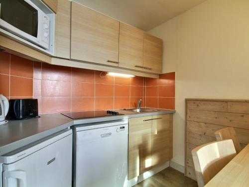une cuisine avec des armoires en bois, un évier et une table dans l'établissement Grand studio-cabine près des pistes, balcon, vue montagne - FR-1-455-214, à La Plagne Tarentaise
