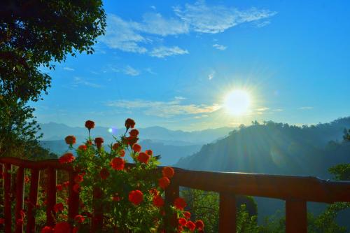 a view of the mountains from a fence with flowers at Rainbow Sky Cottage in Ella