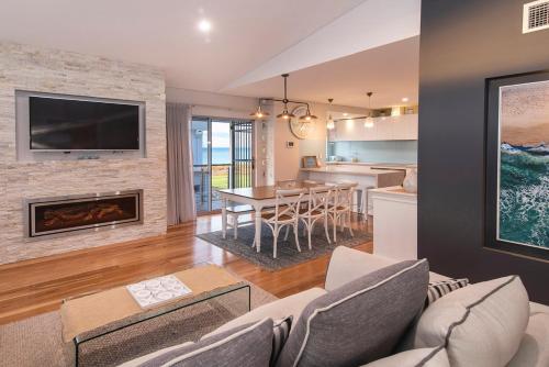 a living room with a fireplace and a dining room at Busselton Beach House in Busselton