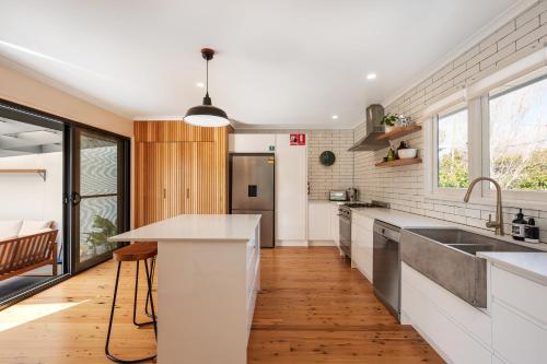 a kitchen with white counters and a wooden floor at 'Mudgee Burrow' A Stylish Central Family Stay in Mudgee